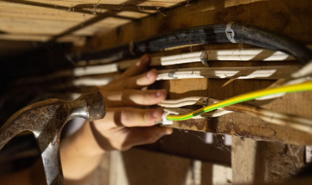 Electrician pulling cable through ceiling joists